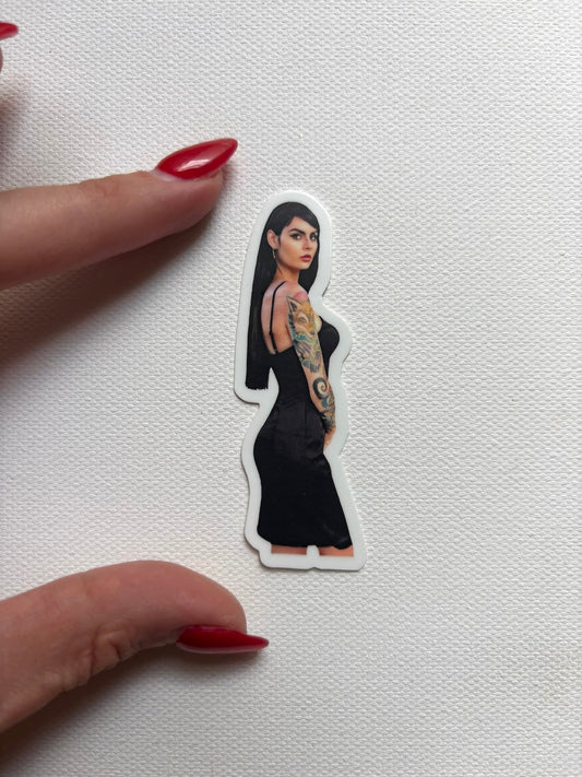 Sticker of a woman with long black hair in a black dress with tattoos. 