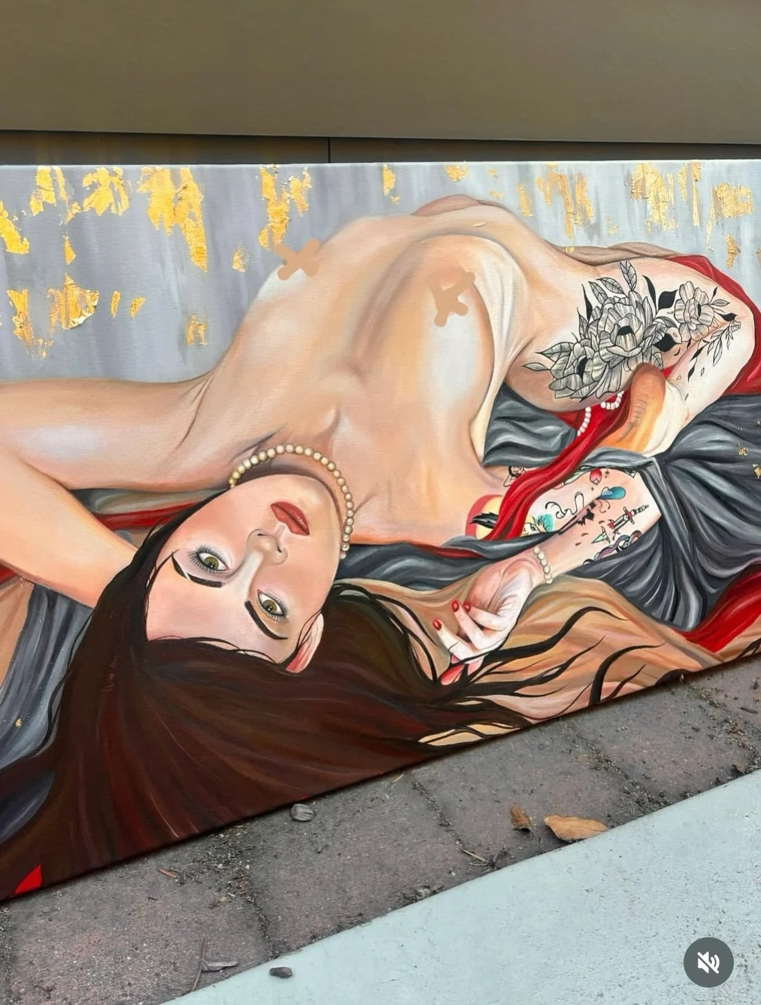 Artistic depiction of a reclining woman with tattoos on a textured wall.