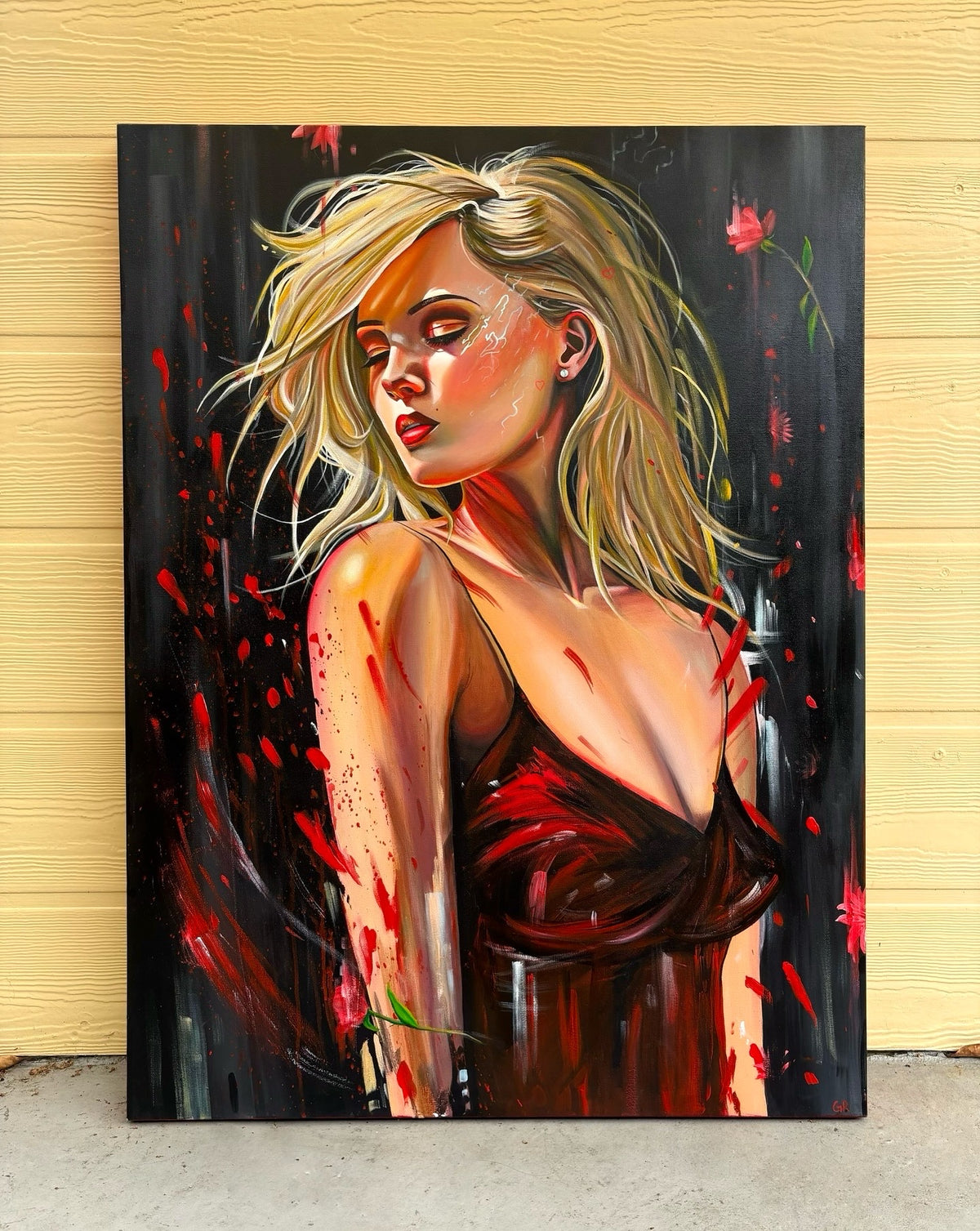 An oil painting of a blonde woman in a red dress, against a black background. The painting is leaning against a wall. 