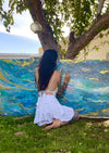 Woman painting a large abstract mural outdoors on a sunny day.