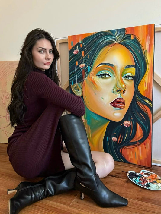 Gracey Ripa sitting in front of a painting she made of an abstract and colorful woman's face. 