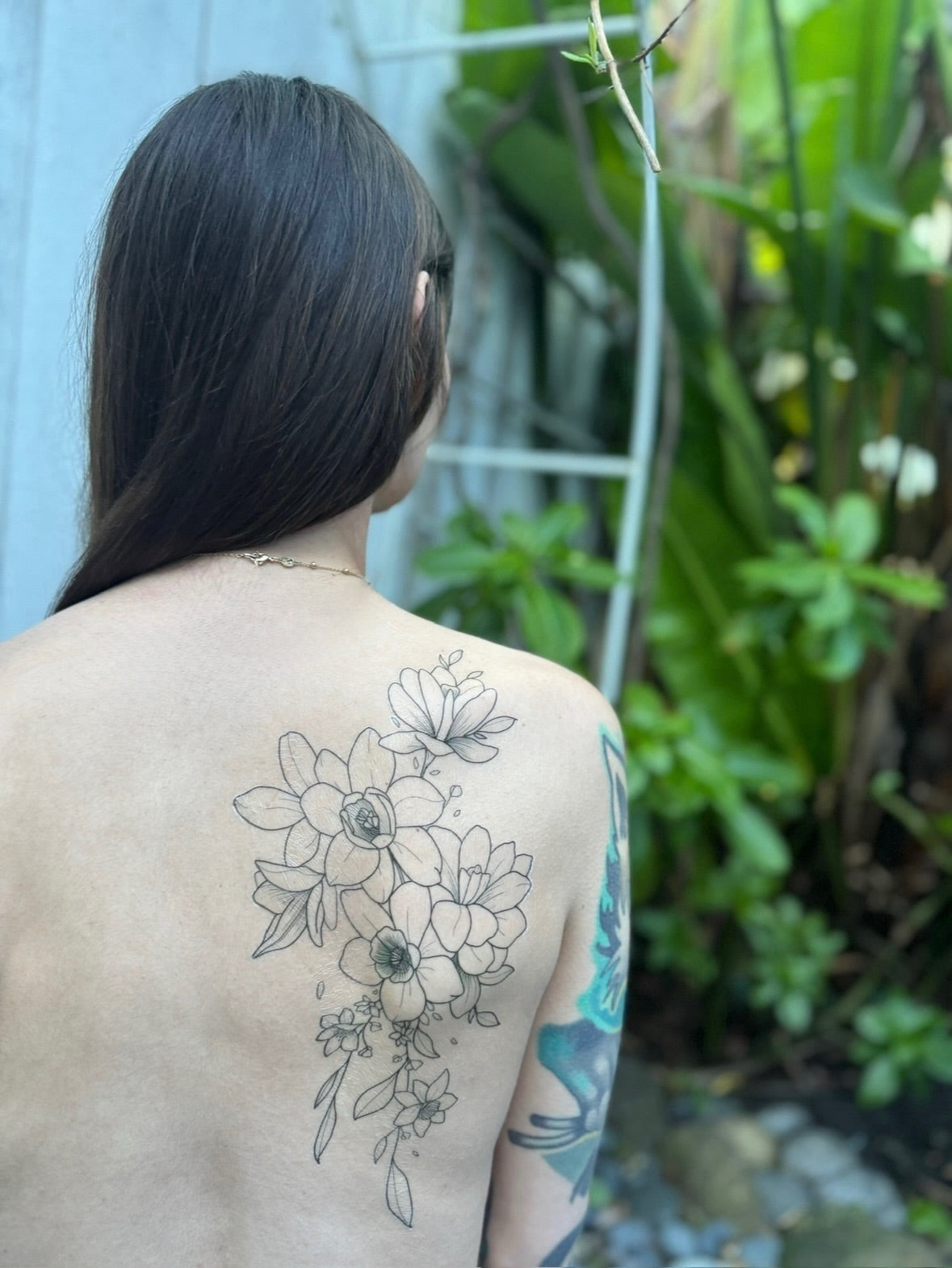 Gracey Ripa posing with a beautiful, decorative, floral temporary tattoo on her back.