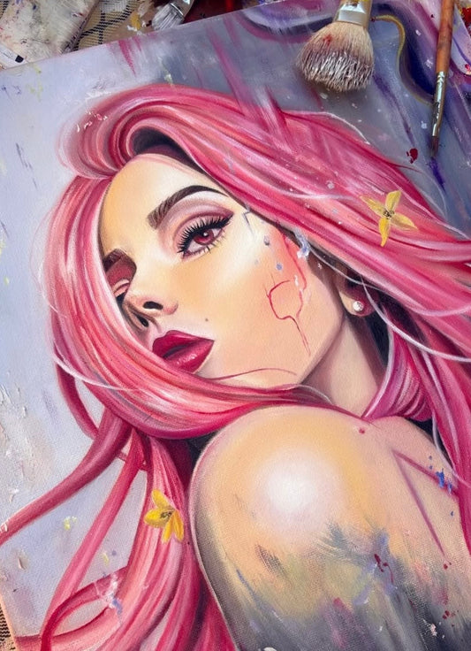 Close up picture of an oil painting of a pretty woman with pink hair and makeup, surrounded by paintbrushes and artistic elements.