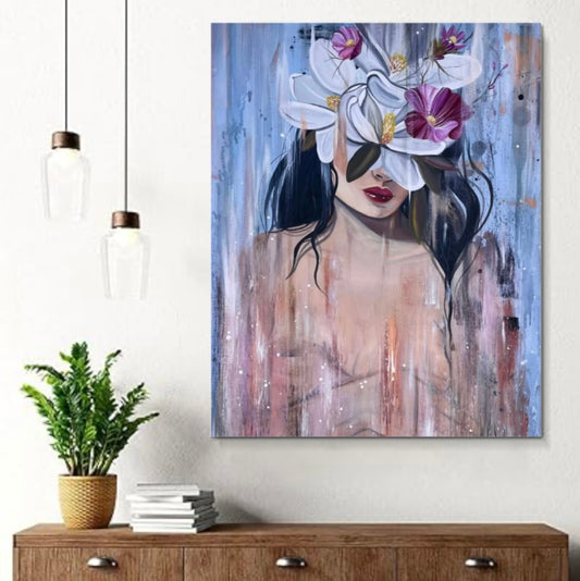 A vertical canvas wall art print featuring an abstract painting of a woman with white flowers over her eyes, styled in a modern living room setting above a wooden console table with a potted plant.