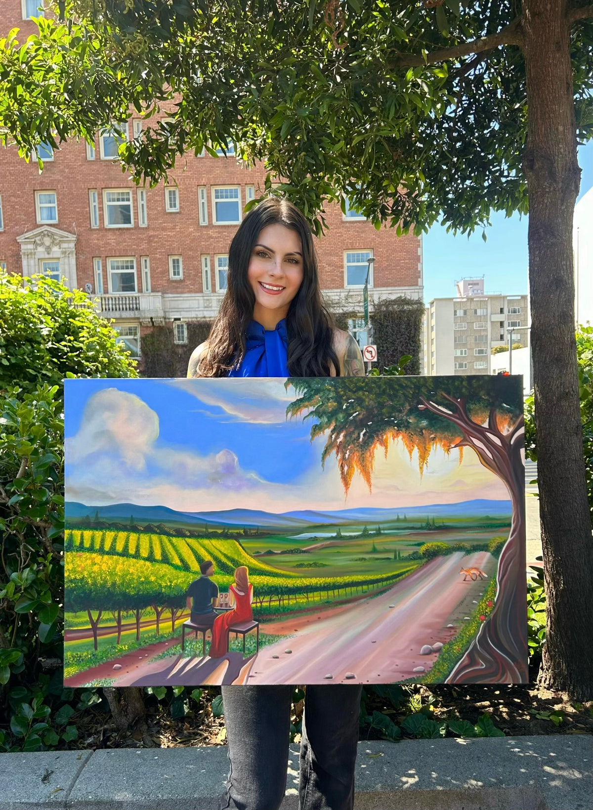 Gracey Ripa holding the large painting of “The Winery” oil painting. 